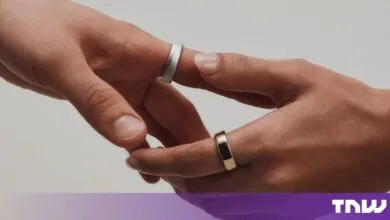 Two hands gently reach toward each other, both wearing minimalist silver and gold smart rings.