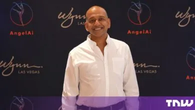 Pavan Agarwal smiling in a white shirt in front of a branded backdrop