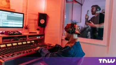 Sound engineer at a mixing desk while a vocalist sings in a studio booth
