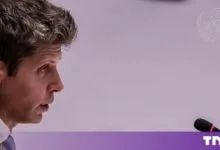 Sam Altman in profile view speaking into a microphone at an official meeting.