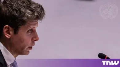 Sam Altman in profile view speaking into a microphone at an official meeting.