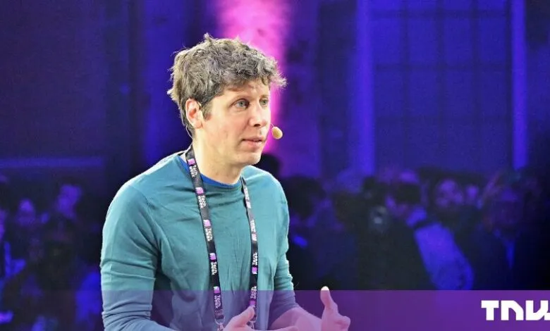 Sam Altman speaking on stage at a technology conference with blue lighting