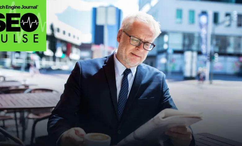 A businessman in a suit reads a newspaper and drinks coffee outdoors.