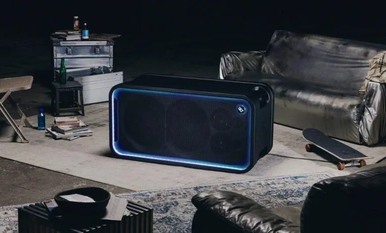 Black Sony wireless party speaker with glowing blue LED lighting in a dimly lit industrial loft setting.