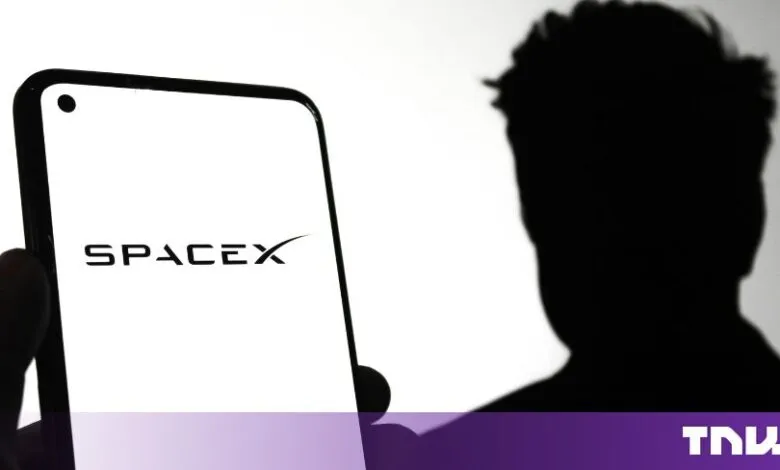 Smartphone displaying the SpaceX logo with a silhouetted figure of Elon Musk in the background.