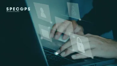 Close-up of hands typing on a laptop with translucent cybersecurity icons floating above the keys.