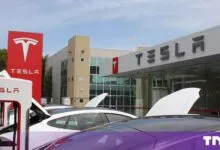Exterior view of a Tesla dealership and charging station with parked electric cars.
