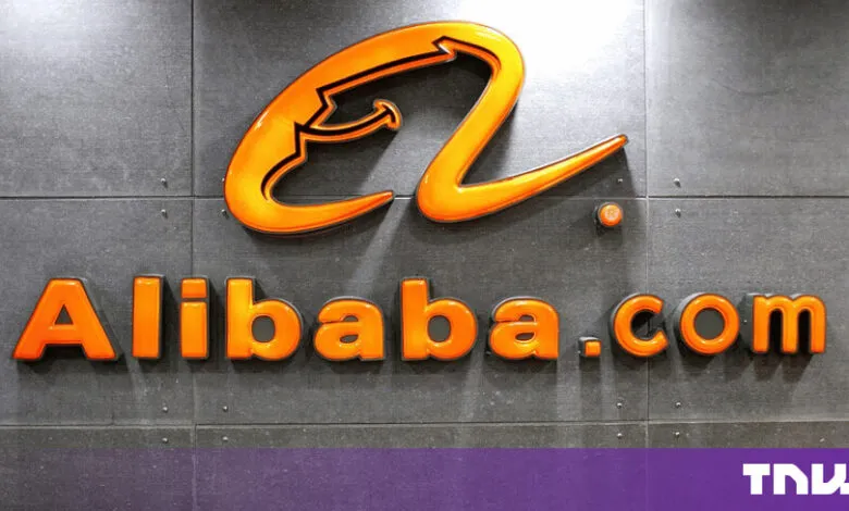 Bright orange Alibaba.com logo mounted on a dark textured grey wall