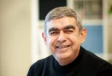 Close-up portrait of businessman and technologist Vishal Sikka smiling in a black turtleneck.