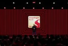 A presenter stands on a stage before a large red Snapdragon Sound screen with an audience watching.