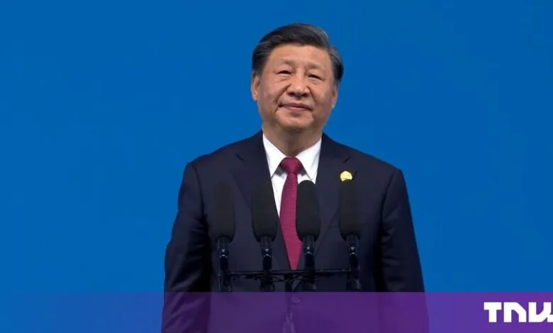 Chinese President Xi Jinping speaking at a podium against a blue background