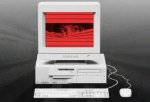 Vintage computer monitor with eyes peering through red blinds