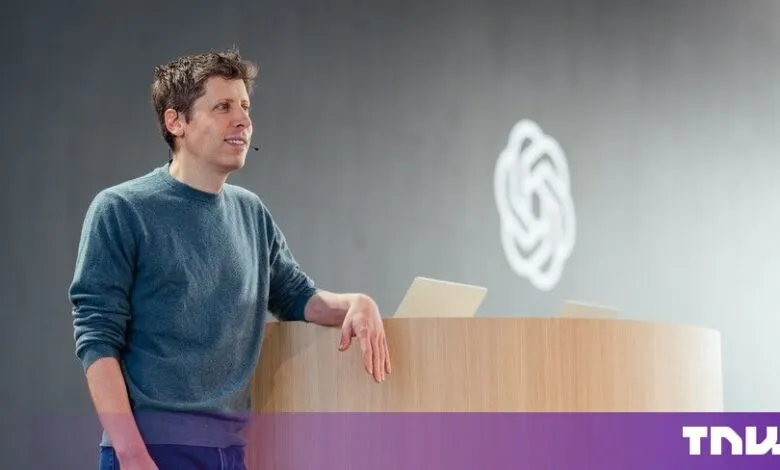 Sam Altman leaning on a podium in front of a grey wall with the OpenAI logo