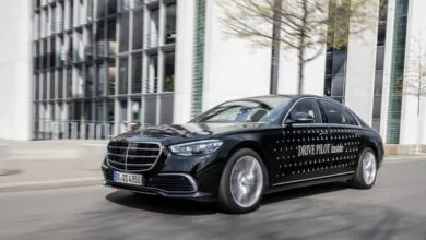 Black Mercedes-Benz sedan driving on a city street with 'DRIVE PILOT inside' text on the side