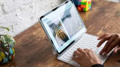 A person types on a white Magic Keyboard attached to an Apple iPad Pro on a wooden desk.