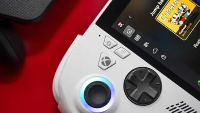 Close-up of a white handheld gaming device with glowing blue thumbstick and directional pad.