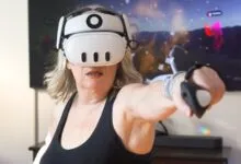 An older woman wearing a white VR headset punches forward with a controller in her living room.