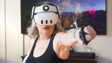 An older woman wearing a white VR headset punches forward with a controller in her living room.