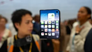 Close-up of a futuristic foldable smartphone with vibrant iOS-style home screen apps.