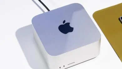 Close-up of a silver Apple Mac Studio computer on a white desk with a keyboard nearby.