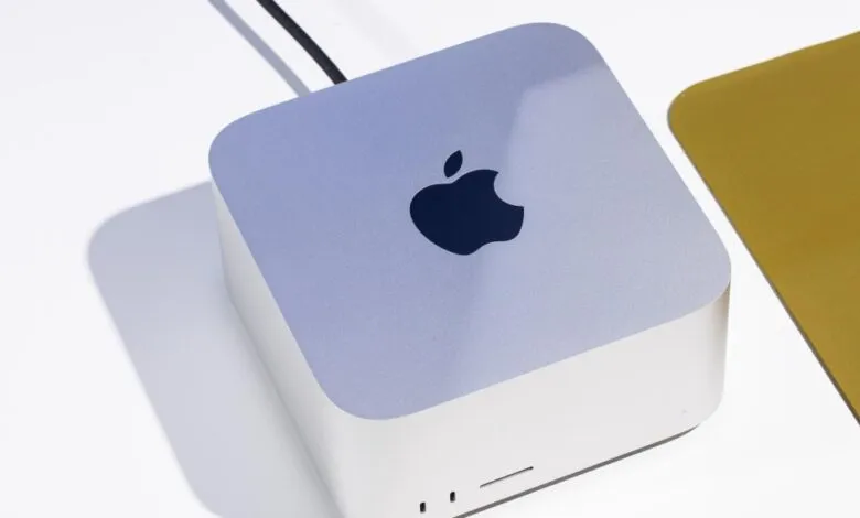Close-up of a silver Apple Mac Studio computer on a white desk with a keyboard nearby.