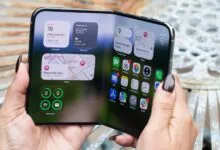Person holding a futuristic foldable smartphone with a glowing touchscreen interface.