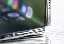 Close-up of a foldable smartphone hinge and flexible display showing blurry app icons