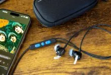Bose wired earbuds with inline controls next to a smartphone displaying The Beatles album Rubber Soul.