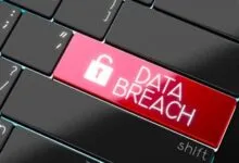 Close-up of a black keyboard featuring a glowing red key that reads DATA BREACH with an open padlock icon.