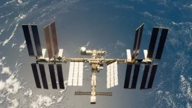 The International Space Station orbits Earth, showcasing its massive solar arrays against a blue backdrop.