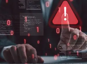 Businessman touching a digital red warning sign surrounded by code and binary numbers