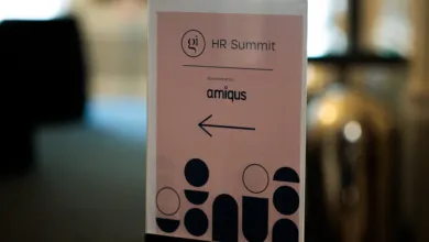 Vertical sign pointing left for the HR Summit, sponsored by amiquus with geometric patterns.