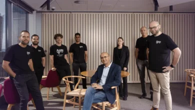 Diverse team of eight professionals posing together in a modern corporate office setting.
