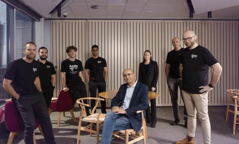 Diverse team of eight professionals posing together in a modern corporate office setting.
