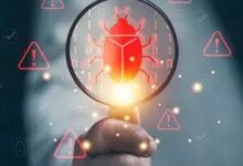 A hand holds a magnifying glass over a glowing red digital bug symbol amidst binary code and warning triangles.
