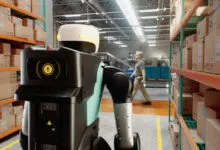 Agility Digit humanoid robot working alongside a human worker in a busy warehouse