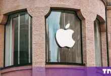 Silver Apple logo displayed on the glass window of a historic stone building facade