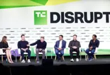 Panelists seated on stage at the TechCrunch Disrupt conference with a large logo backdrop.