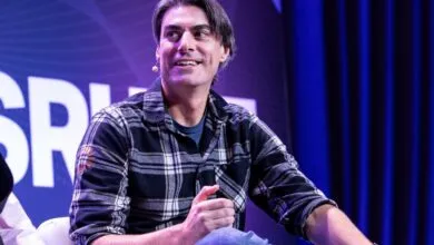 Brandon Sorbom smiling while speaking on stage at a conference in a plaid shirt