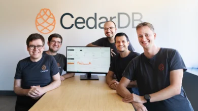 Five CedarDB founders smiling around a conference table with a monitor