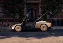 Tesla Cybercab parked on a city street with its gull-wing doors and trunk open in the evening.