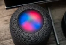 Top-down view of a smart speaker with glowing blue and red lights on the touch surface.