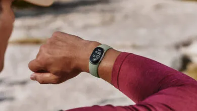 Person wearing a fitness tracker with a green band and digital display on their wrist outdoors.