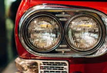 Close-up of dual circular headlights and chrome trim on a vibrant red vintage Japanese car