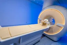 Modern MRI scanner machine with examination table in a blue-lit clinical room