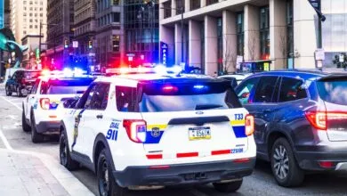 Philadelphia police cars with flashing lights responding to a city emergency on a street.