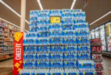 Massive display of bottled water cases stacked neatly inside a grocery store aisle.