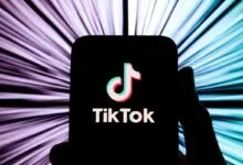 A smartphone displaying the TikTok app logo against a vibrant, light-streaked background.