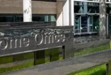 Polished metallic sign with embossed text reading Home Office outside a modern building.