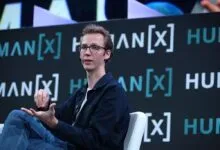Andrej Karpathy speaking at the HumanX conference, gesturing while seated on stage.